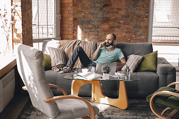 Image showing Young man doing yoga at home while being quarantine and freelance working