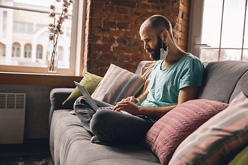 Image showing Young man doing yoga at home while being quarantine and freelance working