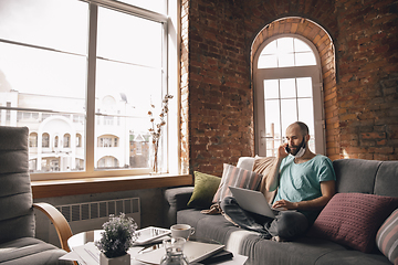 Image showing Young man doing yoga at home while being quarantine and freelance working