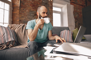 Image showing Young man doing yoga at home while being quarantine and freelance working