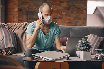 Image showing Young man doing yoga at home while being quarantine and freelance working