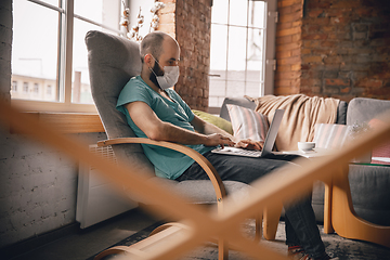 Image showing Young man doing yoga at home while being quarantine and freelance working