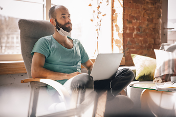 Image showing Young man doing yoga at home while being quarantine and freelance working