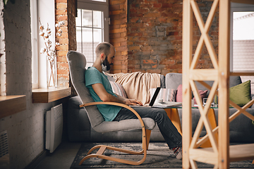 Image showing Young man doing yoga at home while being quarantine and freelance working