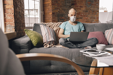 Image showing Young man doing yoga at home while being quarantine and freelance working