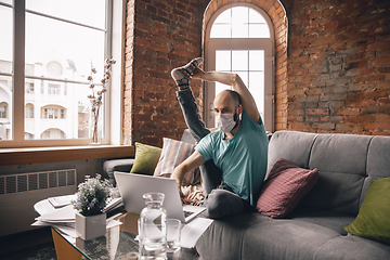 Image showing Young man doing yoga at home while being quarantine and freelance working