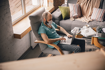 Image showing Young man doing yoga at home while being quarantine and freelance working