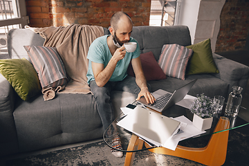 Image showing Young man doing yoga at home while being quarantine and freelance working