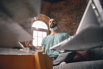 Image showing Young man doing yoga at home while being quarantine and freelance working