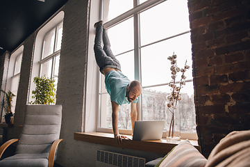 Image showing Young man doing yoga at home while being quarantine and freelance working