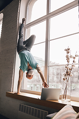 Image showing Young man doing yoga at home while being quarantine and freelance working