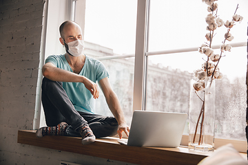 Image showing Young man doing yoga at home while being quarantine and freelance working