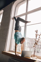 Image showing Young man doing yoga at home while being quarantine and freelance working