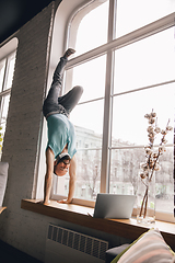 Image showing Young man doing yoga at home while being quarantine and freelance working