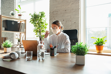 Image showing Woman working in office alone during coronavirus or COVID-19 quarantine, wearing face mask