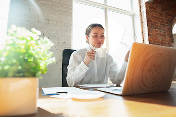 Image showing Woman working in office alone during coronavirus or COVID-19 quarantine, wearing face mask