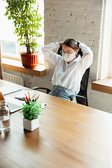 Image showing Woman working in office alone during coronavirus or COVID-19 quarantine, wearing face mask