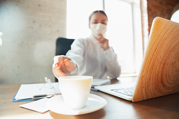 Image showing Woman working in office alone during coronavirus or COVID-19 quarantine, wearing face mask