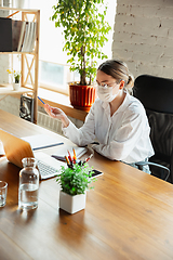 Image showing Woman working in office alone during coronavirus or COVID-19 quarantine, wearing face mask