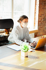 Image showing Woman working in office alone during coronavirus or COVID-19 quarantine, wearing face mask