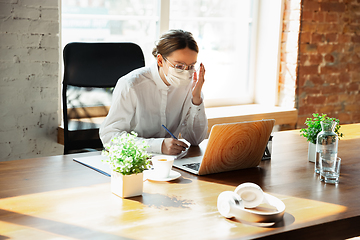 Image showing Woman working in office alone during coronavirus or COVID-19 quarantine, wearing face mask