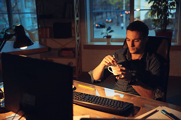 Image showing Man working in office alone during coronavirus or COVID-19 quarantine, staying to late night