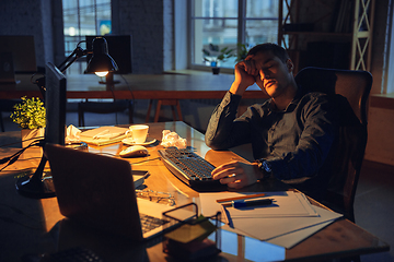 Image showing Man working in office alone during coronavirus or COVID-19 quarantine, staying to late night