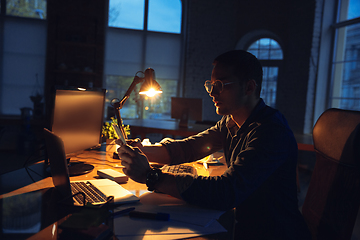 Image showing Man working in office alone during coronavirus or COVID-19 quarantine, staying to late night