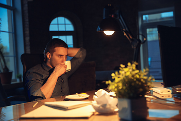 Image showing Man working in office alone during coronavirus or COVID-19 quarantine, staying to late night