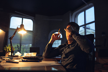 Image showing Man working in office alone during coronavirus or COVID-19 quarantine, staying to late night