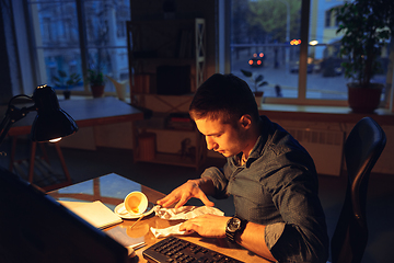 Image showing Man working in office alone during coronavirus or COVID-19 quarantine, staying to late night