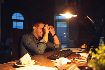 Image showing Man working in office alone during coronavirus or COVID-19 quarantine, staying to late night