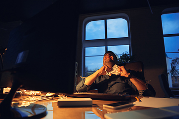 Image showing Man working in office alone during coronavirus or COVID-19 quarantine, staying to late night