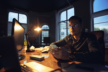 Image showing Man working in office alone during coronavirus or COVID-19 quarantine, staying to late night