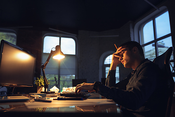 Image showing Man working in office alone during coronavirus or COVID-19 quarantine, staying to late night