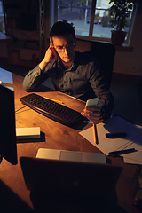 Image showing Man working in office alone during coronavirus or COVID-19 quarantine, staying to late night