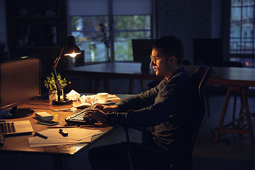 Image showing Man working in office alone during coronavirus or COVID-19 quarantine, staying to late night