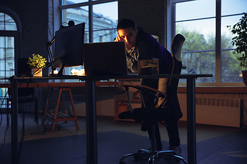 Image showing Man working in office alone during coronavirus or COVID-19 quarantine, staying to late night