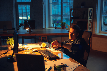 Image showing Man working in office alone during coronavirus or COVID-19 quarantine, staying to late night