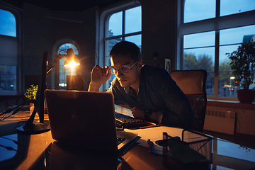 Image showing Man working in office alone during coronavirus or COVID-19 quarantine, staying to late night