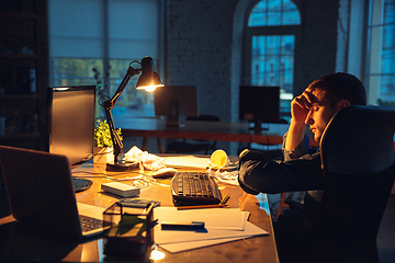 Image showing Man working in office alone during coronavirus or COVID-19 quarantine, staying to late night