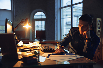 Image showing Man working in office alone during coronavirus or COVID-19 quarantine, staying to late night