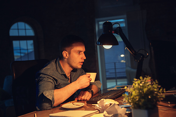 Image showing Man working in office alone during coronavirus or COVID-19 quarantine, staying to late night