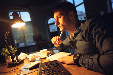 Image showing Man working in office alone during coronavirus or COVID-19 quarantine, staying to late night