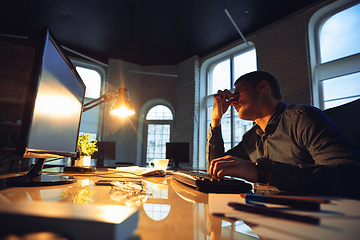 Image showing Man working in office alone during coronavirus or COVID-19 quarantine, staying to late night