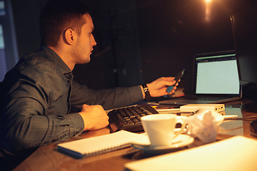 Image showing Man working in office alone during coronavirus or COVID-19 quarantine, staying to late night