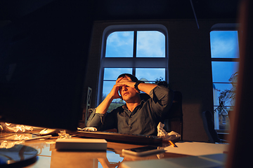 Image showing Man working in office alone during coronavirus or COVID-19 quarantine, staying to late night