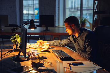 Image showing Man working in office alone during coronavirus or COVID-19 quarantine, staying to late night