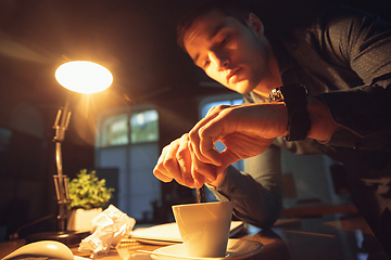 Image showing Man working in office alone during coronavirus or COVID-19 quarantine, staying to late night