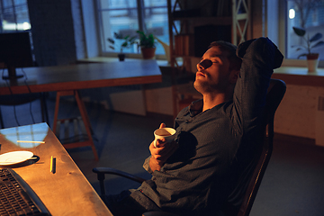 Image showing Man working in office alone during coronavirus or COVID-19 quarantine, staying to late night